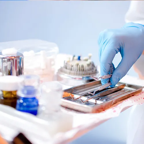 gloved hand and tray with dental tools