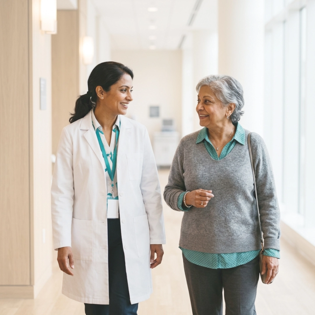 Doctor walking with elderly patient in clinic hallway, smiling and talking