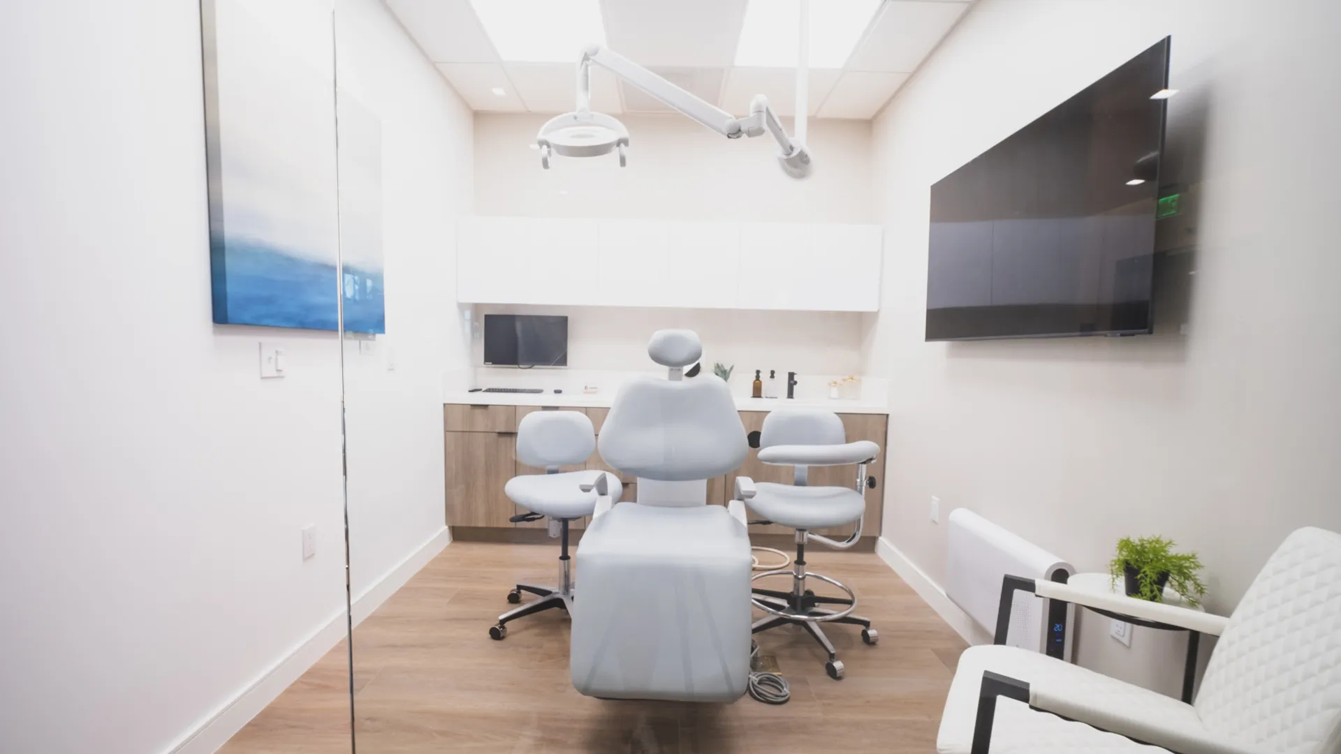 Dental treatment room at Aviara Centers with patient chair, exam light, wall-mounted screen, and consultation seating