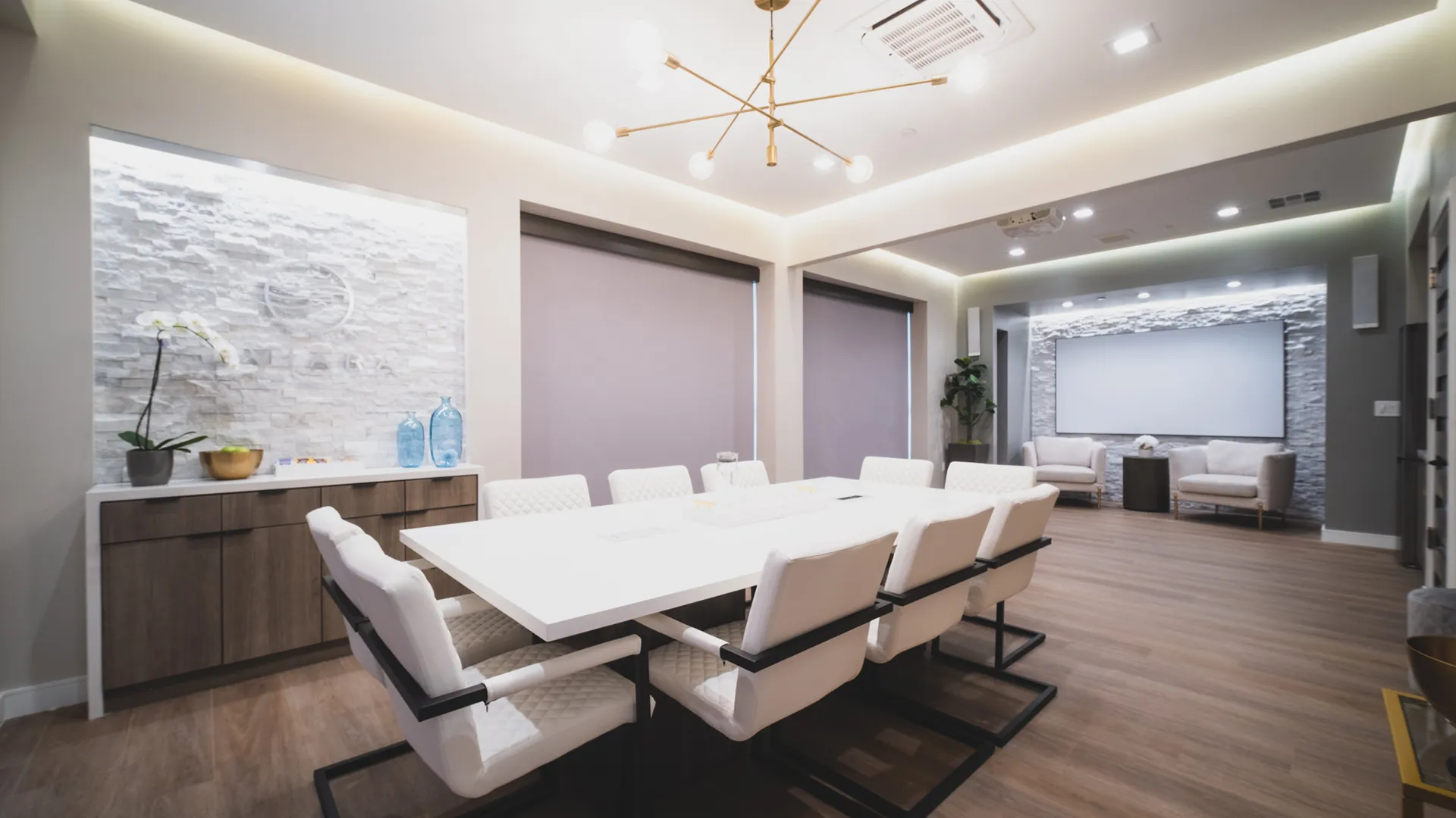 Conference room at Aviara Centers with long white meeting table, upholstered chairs, Aviara feature wall, and presentation screen