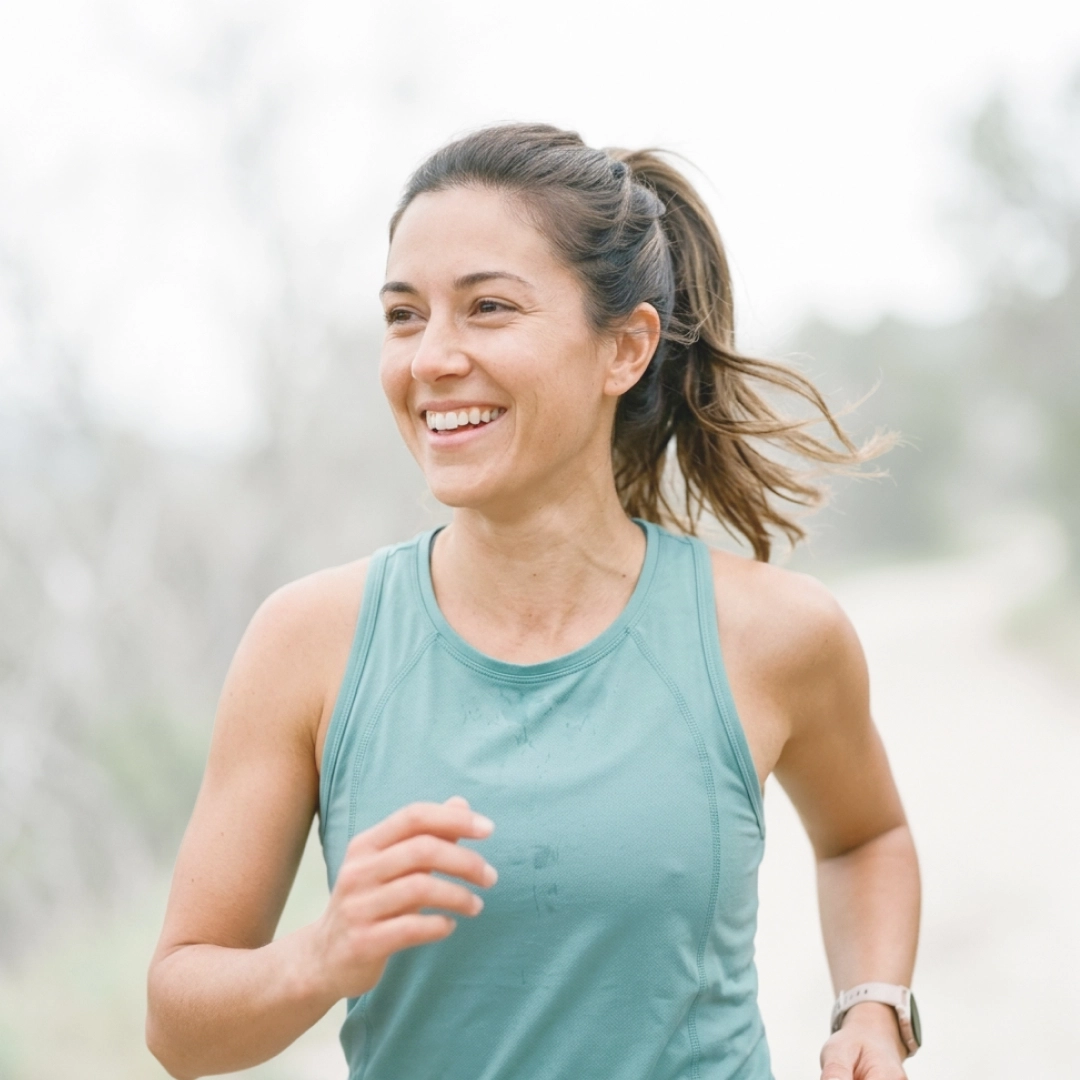 Woman jogging outdoors smiling, representing improved health and vitality