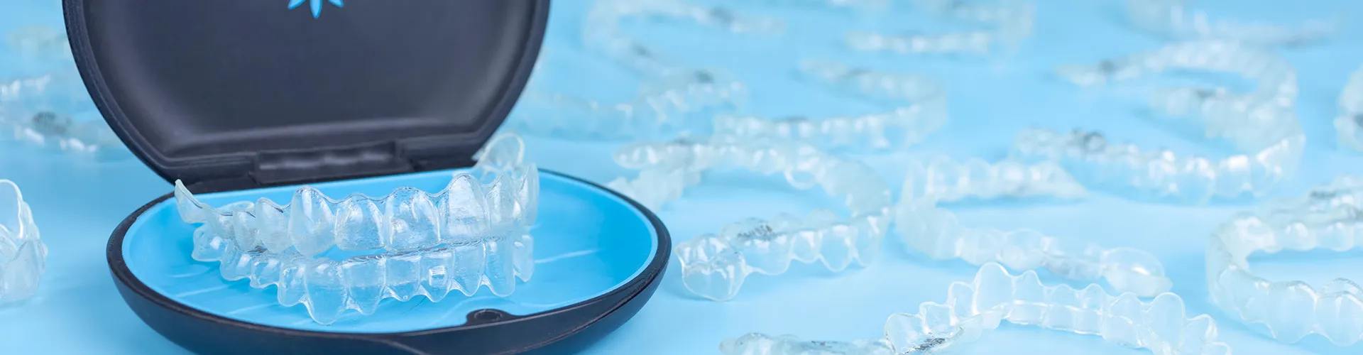 clear aligners in invisalign case surrounded by aligners