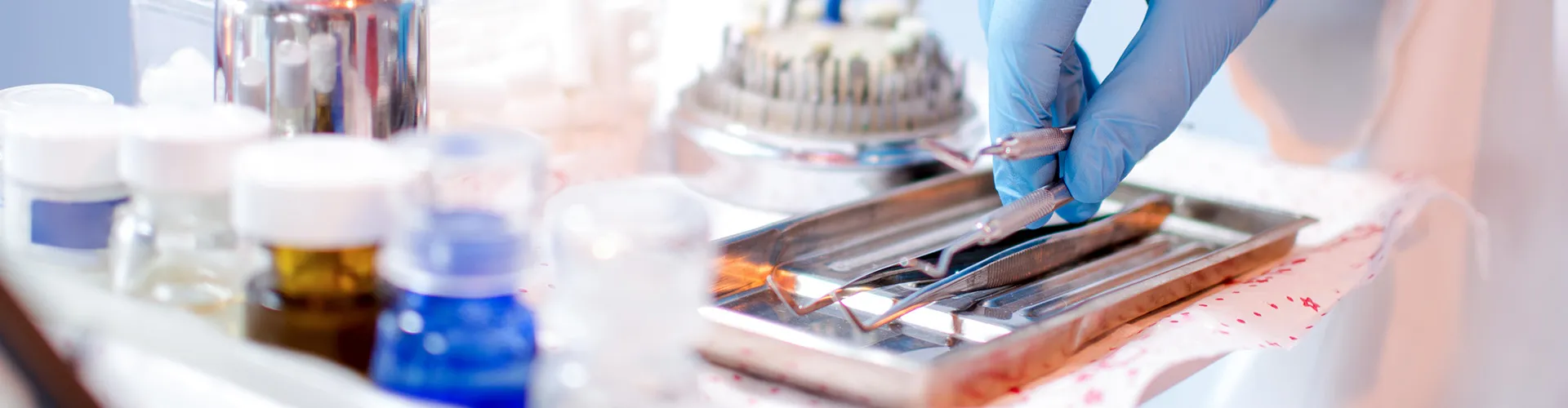 gloved hand and tray with dental tools