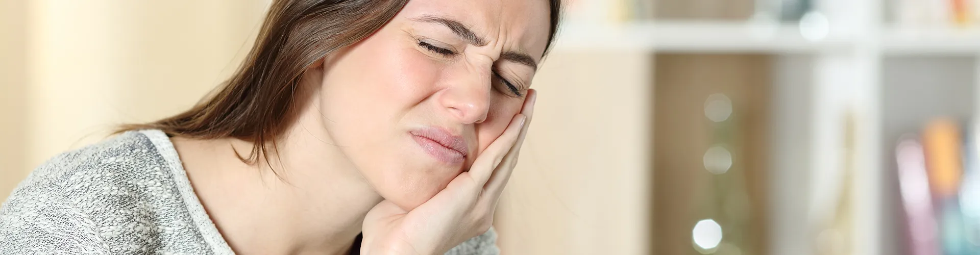 woman holding her jaw in pain